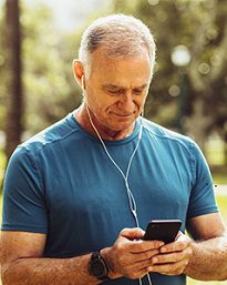 Man in blue shirt using smartphone outdoors